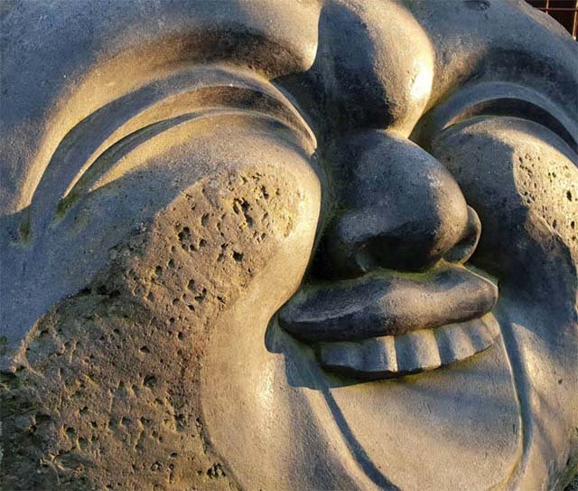 Steinskulptur eines lachenden Gesichts