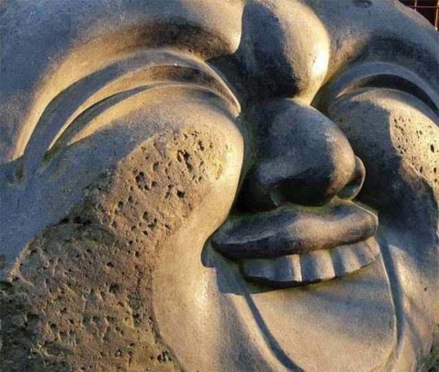 Steinskulptur eines lachenden Gesichts