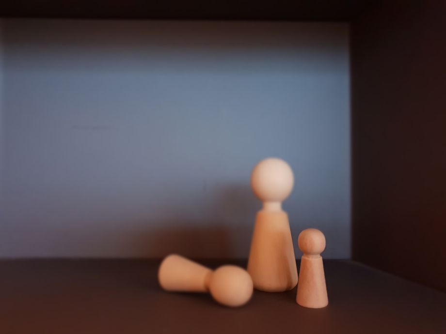 Holzfiguren, eine liegend, zwei stehend – ein Symbol für Trauma